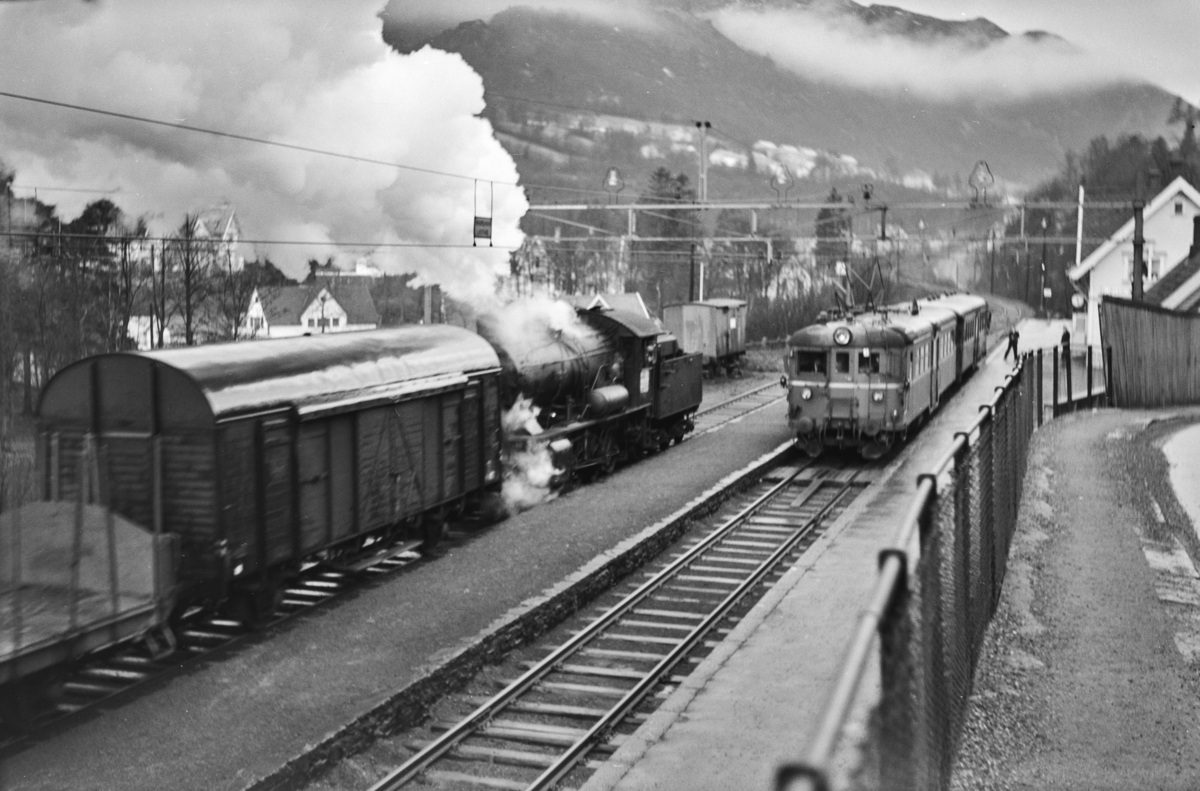 Kryssing på Fjøsanger stasjon mellom lokaltog reting Voss, tog 624, og kipptog til Bergen. Kipptoget trekkes av damplokomotiv type 33a nr. 300. I lokaltoget elektrisk motorvogn Bmeo 65 og styrevogn BFo4b.