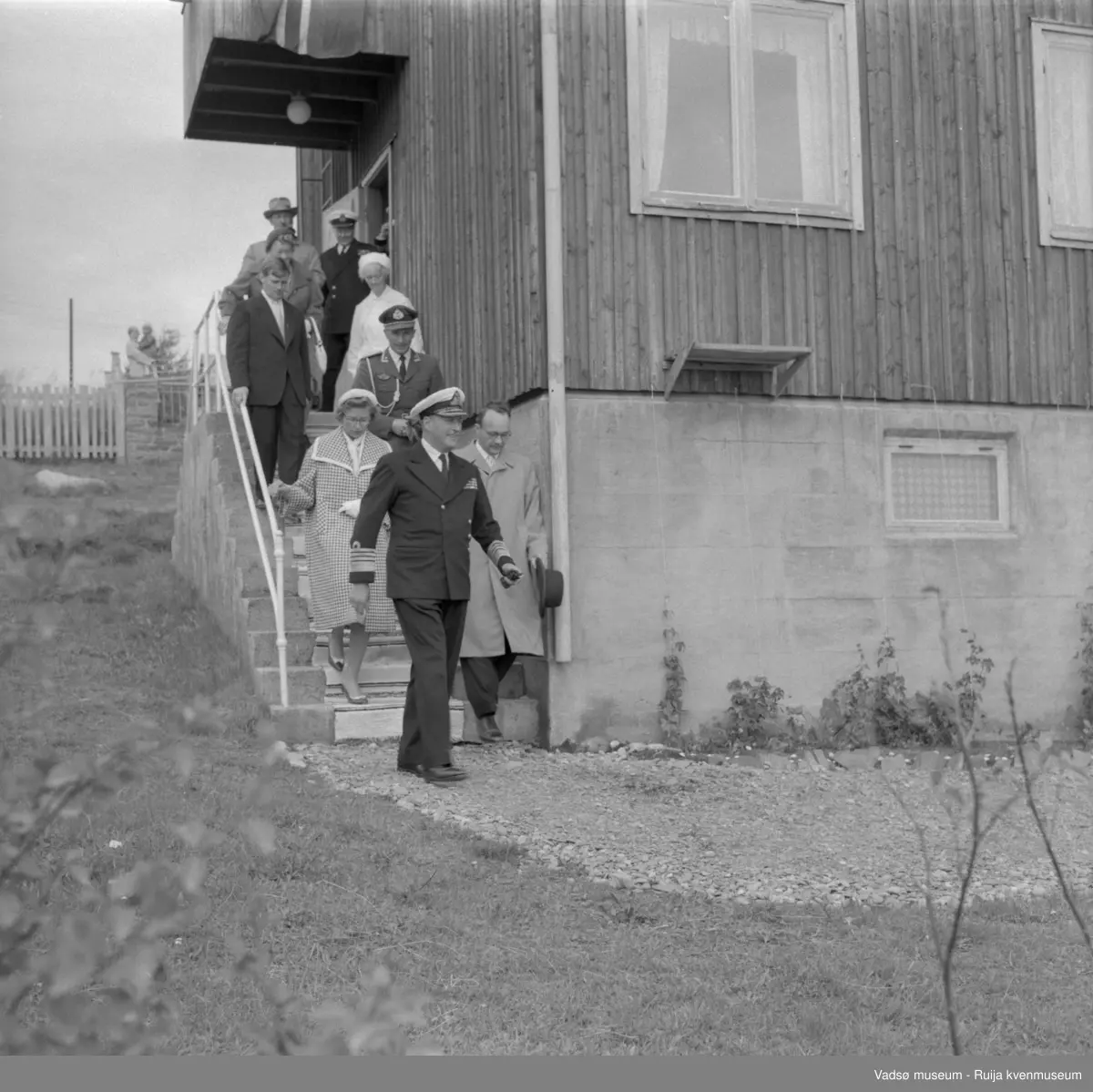 Vadsø juli 1959. Kongebesøk. Kongen med følge på vei ned trappa på gamlehjemmet Alders hvile. Kong Olav, ordfører Anders Aune og prinsesse Astrid nærmest