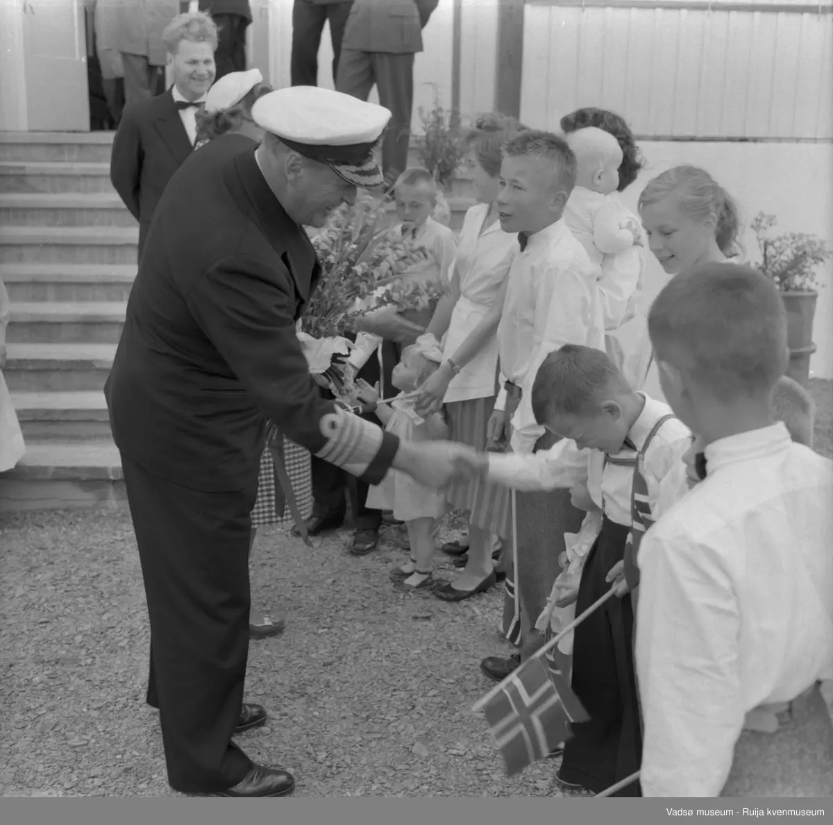 Vestre Jakobselv juli 1959. Kongebesøk på barnehjemmet Vårsol. Kongen hilser på barna. Bak Kongen skimtes prinsesse Astrid, og bak prinsessen står Anaton Strand.