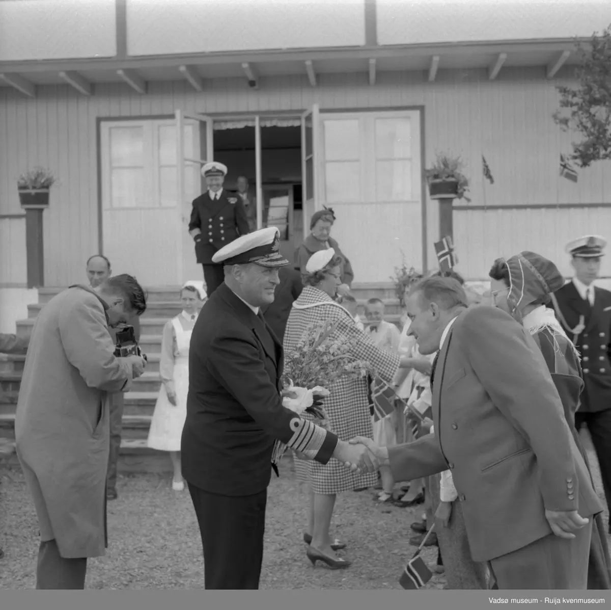 Vestre Jakobselv juli 1959. Kongebesøk på barnehjemmet Vårsol. Kongen hilser på Gunnar Harila.. Til venstre for Kongen søster Gunvor, til høyre prinsesse Astrid. Bak fotografen står ordfører Henry Karlsen.