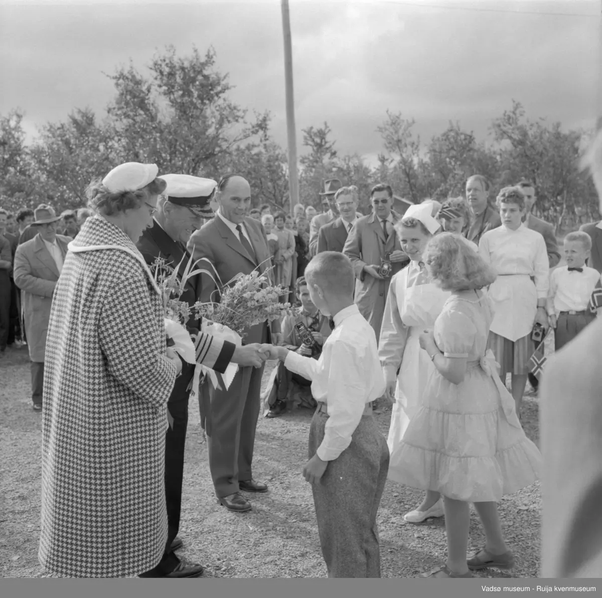 Vestre Jakobselv juli 1959. Kongebesøk på barnehjemmet Vårsol.  Blomsteroverrekking. Til venstre for Kongen prinsesse Astrid. Til høyre blant annet ordfører Henry Karlsen og søster Gunvor.