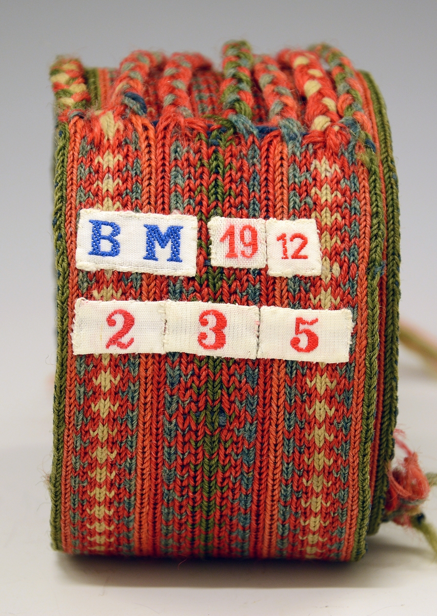 Belte til folkedrakt, brikkevevet. Frynser i den ene enden, de er flettet. Den andre enden er det renning uten avslutning.