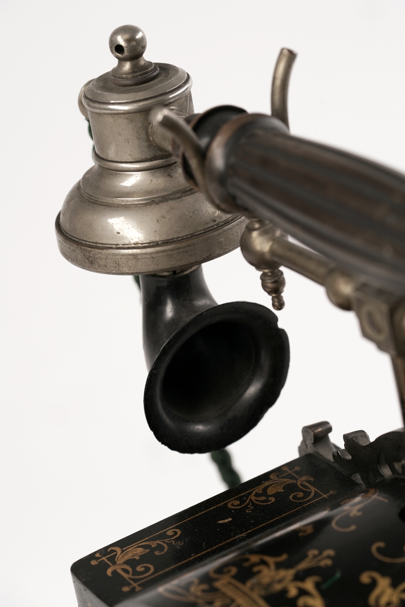 Telefonapparat med koblingsskive. Sort og gull med forsiringer.