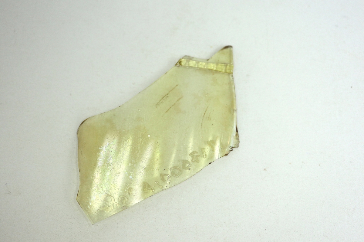 Tre delar av ett brungult, mångkantigt och optikblåst passglas med pålagda strierade trådar.