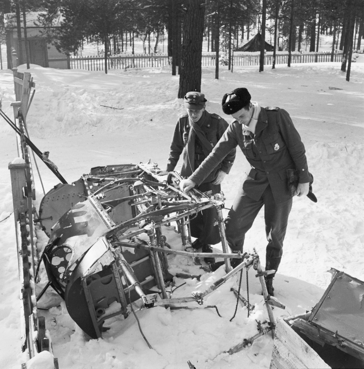 Två militärer inspekterar delar av det havererade flygplanet Hawker Hart märkt blå Z vid F 19, Svenska frivilligkåren i Finland. Till höger flygförare Gunnar Färnström.