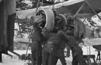 Motorbyte på flygplan Gloster Gladiator vid F 19, Svenska frivilligkåren i Finland. Tre mekaniker i arbete.