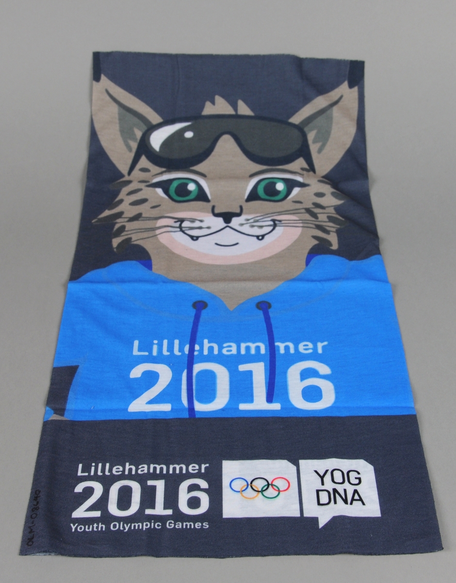 Hals av bommulsstoff som er dekorert med maskotten Sjogg for Ungdoms-OL på Lillehammer 2016. Tørklet ligger i original emballasje med oppskrift på ulike måter å bruke tørklet på.