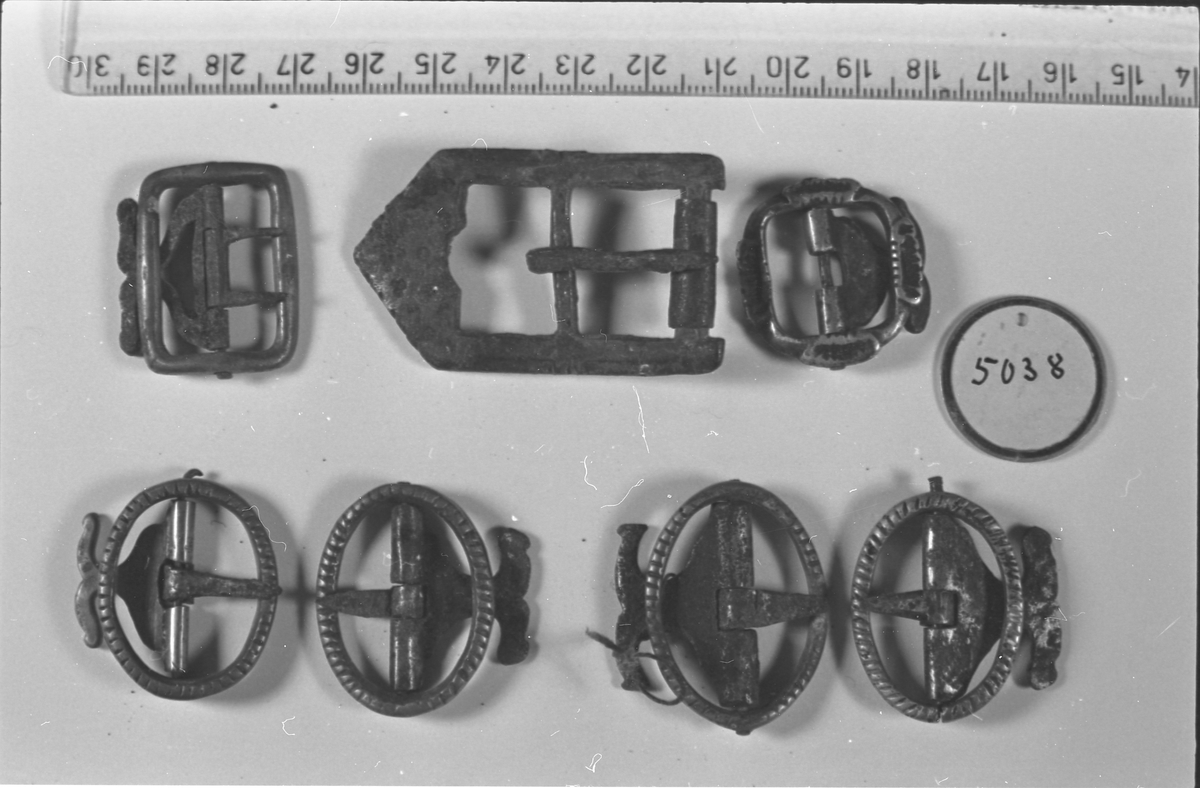 Stølebelte av rødt ullstoff kantet med mørkt ullstoff og med striestoff på innsida. Det er små beltestøler langs hele beltet, som hver har to lauv. Beltespenna har enkel gravert dekor. 