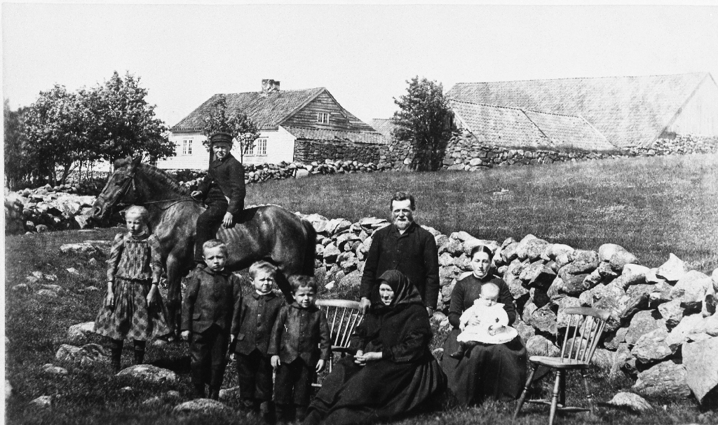 Garden Auglend med familien Sven og Dorthea Auglend i framgrunnen, Haugland øvre bnr. 2..
F. v. : Barnepike Grete Grødem, Søren Sørensen Vestly på hesten, Gabriel Auglend (1887 - 1920), Elling Gabriel Auglend (1889  - 1975), Olav Auglend (1890 - 1957), Sven Gabrielsen Auglend (1855 - 1902), kona Dorthea Maria f. Refve (1860 - 1932) med Ragnvald Auglend (1894 - 1900) på fanget. Kona med skaut er mor til Sven G. Auglend, Gunhild Oline Nilsdotter f. Ualand (1818 - 1899). 
Sonen Sven Auglend (1892 - 1959) låg til sengs med ein brekt fot og var derfor ikkje med på biletet. Ei ku hadde spent han.
Soga vil ha det til at stolen til høgre var bestemt for Gabriel Olsen Mauland (far til Sven G.), men han ville ikkje fotograferast då det var mot hans religiøse overtyding.