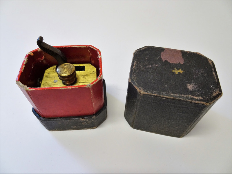 Årelatingsinstrument i metall med tilhørende åttekantet oppbevaringsboks.
 
Instrumentet består av en liten messingkasse med 12 kniver som spennes samtidig med en kraftig fjær koblet til en hane på toppen av kassen. En skrue ved siden av hanen justeres for å oppnå ønsket dybde. En liten knapp på siden av apparatet utløste knivene når instrumentet var plassert der årelatingen skulle gjennomføres, ofte på innsiden av armen.