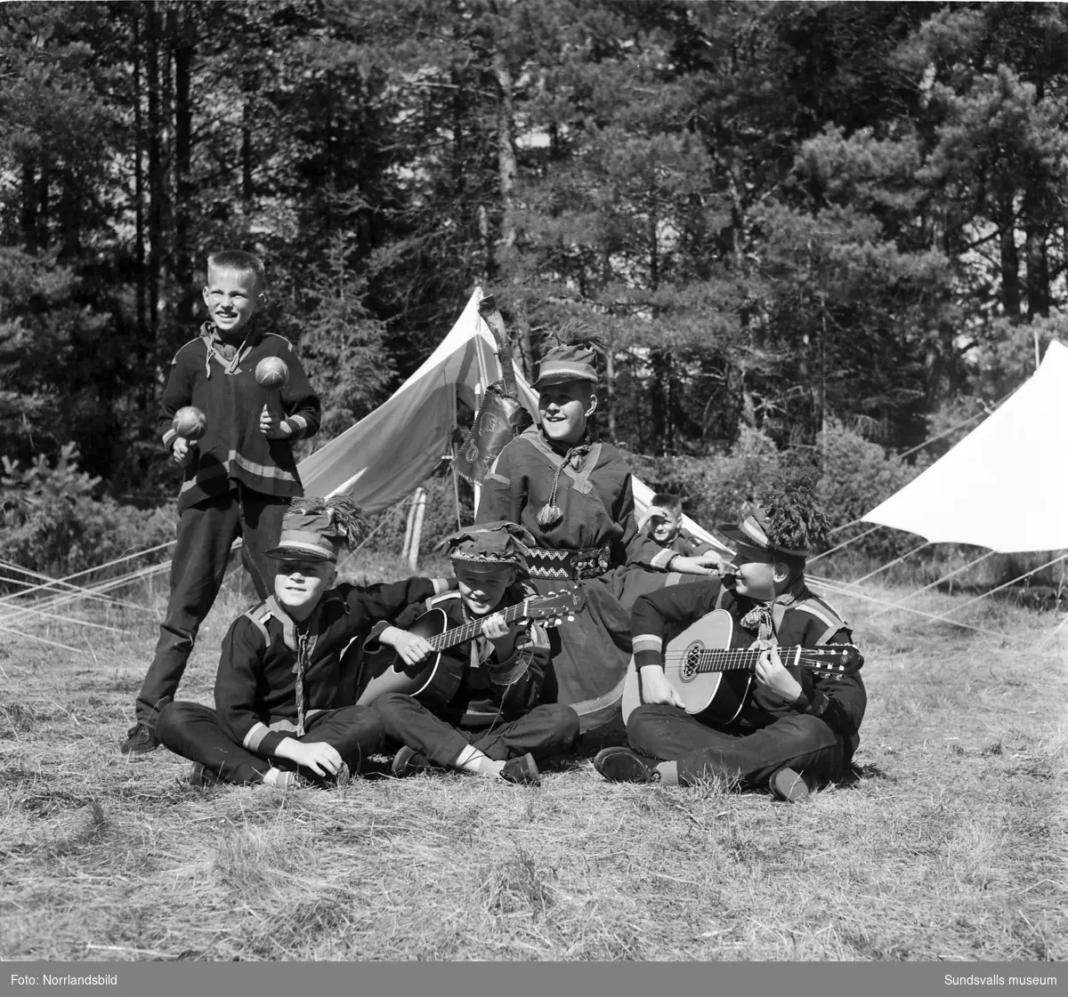 I juli 1959 anordnade Svenska Scoutförbundet sitt stora internationella läger på Rödön utanför Alnö. På första bilden ses lägerledaren Tage Allegård anlända med en grupp pojkscouter för några intensiva veckor på ön. Lägret hade förberetts under ett helt år och dagarna innan hade 70 pojkscouter och ledare hjälpts åt att bygga upp de olika lägerbyarna, som fick namn efter olika fyrar.  SCA hade upplåtit en pråm som låg för ankar i hamnen fylld med de matvaror som krävdes för att mätta de cirka 800 deltagarna.