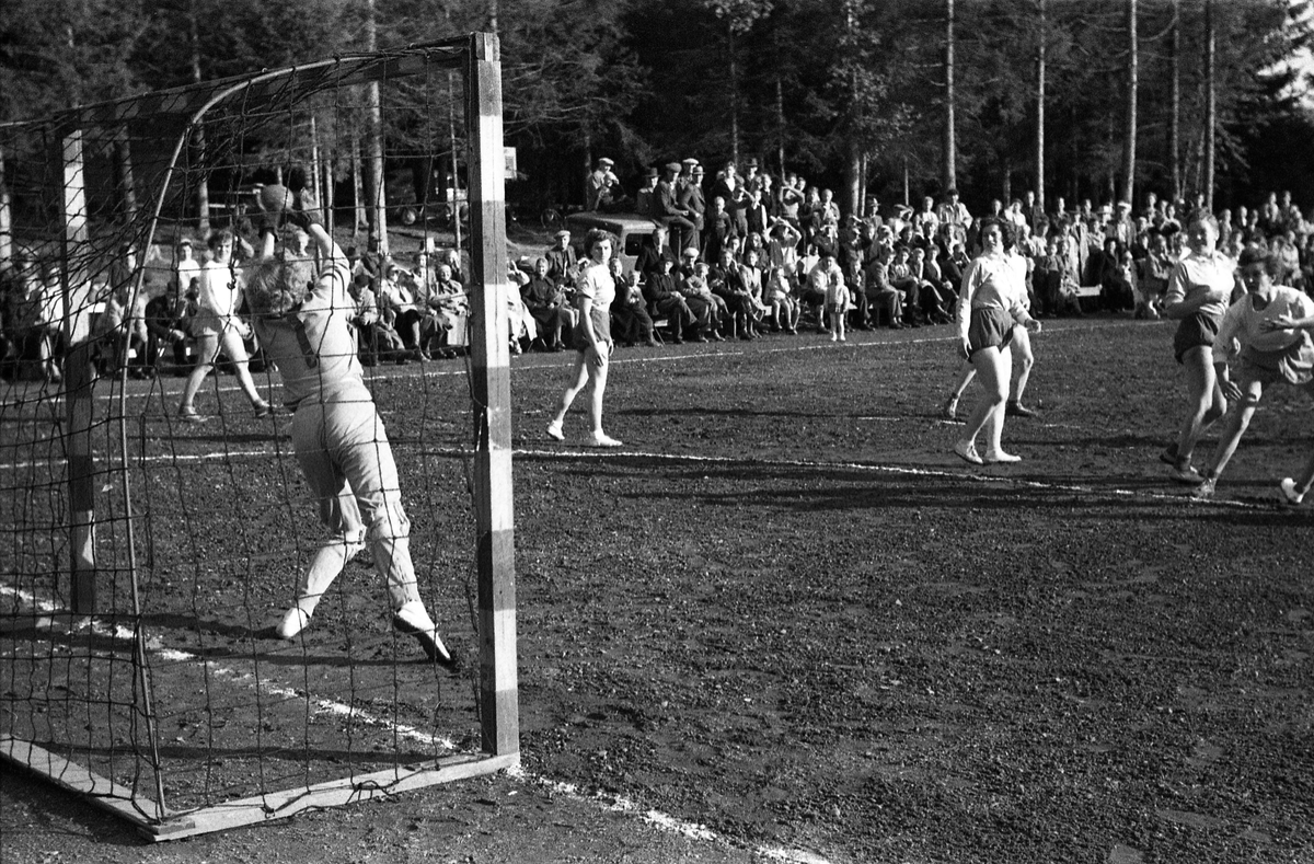 Håndballkamp på Kraby Idrettsplass september 1953. Kampen var kvartfinale i damenes Norgesmesterskap mot Nornen fra Bergen, en kamp Kraby vant og dermed kvlifiserte seg for semifinale. Krabys spillere, i de mørkeste buksene, er identifisert, men for navn henvises til lagbilde TMF-06483.
14 bilder som viser kampsituasjoner og publikum.