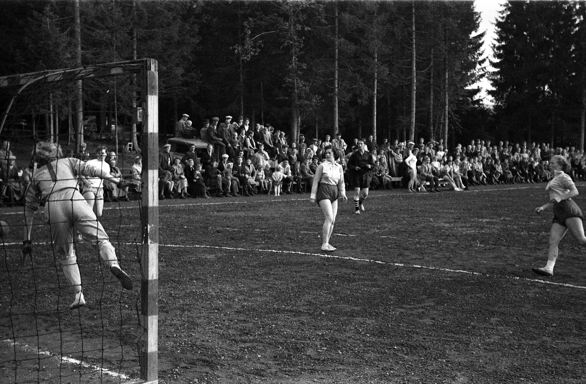 Håndballkamp på Kraby Idrettsplass september 1953. Kampen var kvartfinale i damenes Norgesmesterskap mot Nornen fra Bergen, en kamp Kraby vant og dermed kvlifiserte seg for semifinale. Krabys spillere, i de mørkeste buksene, er identifisert, men for navn henvises til lagbilde TMF-06483.
14 bilder som viser kampsituasjoner og publikum.