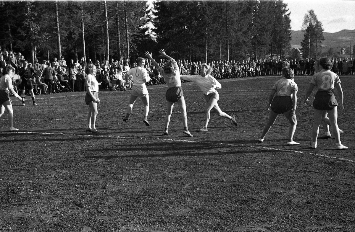 Håndballkamp på Kraby Idrettsplass september 1953. Kampen var kvartfinale i damenes Norgesmesterskap mot Nornen fra Bergen, en kamp Kraby vant og dermed kvlifiserte seg for semifinale. Krabys spillere, i de mørkeste buksene, er identifisert, men for navn henvises til lagbilde TMF-06483.
14 bilder som viser kampsituasjoner og publikum.