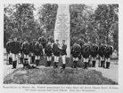 Grupporträtt av korpralskolans elever på Malmen 1891. Uppställning framför minnessten. Avfotografering av bild ur tryck.