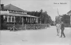 Byggnad i Malmslätts samhälle ca 1910. Café och matservering. Militärer i rörelse. Avfotografering av vykort.