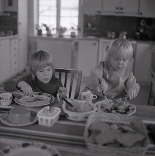 Två barn sitter vid en bord och äter en måltid, 1974.