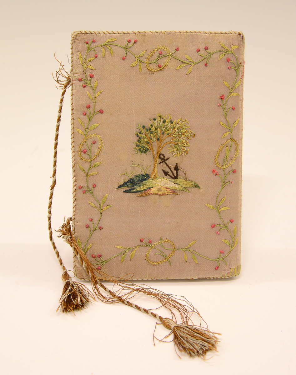 Lommebok i silke med brodert motiv og tekst. Innvendig med tre rom. Permane paaføra med gult og violet silkety med blomebrodering  paa utsidane. Paa framsida stend sauma: H.A. - Erkjendlighedsminde. Paa baksida eit tre, innaat dette eit ankar. Tvunnet silkeband.