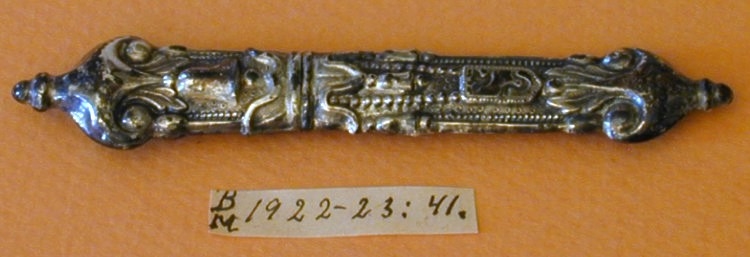 Nålehus i sølv. Drevet dekor, bl.a. med bjeller og våpenskjoldform med fugl og slange. 
Utydelig stempel: Ant. krone og (...)114.