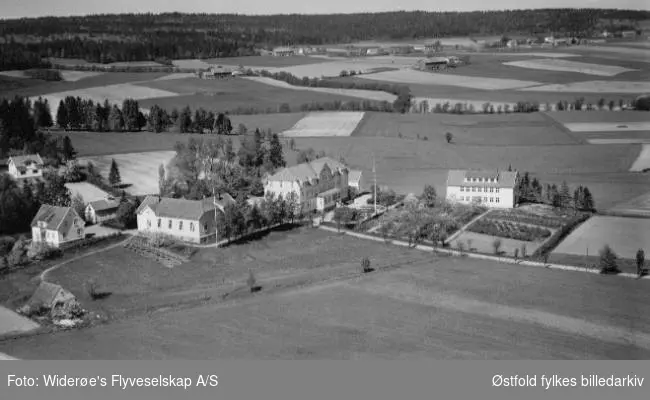 Haugetun ungdomsskole med bolighus til venstre og flere gårder i bakgrunnen. Tatt fra Rolvsøysund/ visterflo.