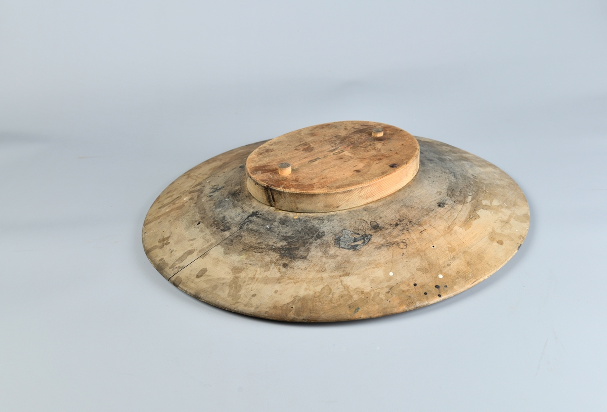 Oval bremblokk med flat topp og nedskrående kanter. På toppen er det to hull der man kan sette fast en hatteblokk for et hattehode. Følger med tilhørende oval og flat blokk med to trenagler som passer. Litt flekkete på over og undersiden, men er generelt i god stand.