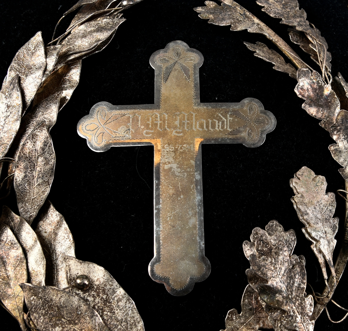 Sølvkrans av laurbær og eikeløv med sløyfe nederst. Mellom de bøyde greinene er det et sølvkors. Kransen er sydd ned på en svart fløyelspute med dusker i hjørnene. Sølvsnor påsydd rundt puta.

Det finnes to like kranser som denne publisert på Digitalt museum. Den ene er udatert, men den andre er også produsert i 1924 - og befinner seg på Mjøsmuseet.