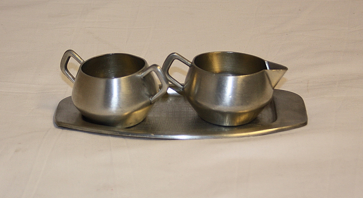 Lite fat med sukkerskål og fløtemugge. Fløtemugge med helletut og hank. Sukkerkopp med to hanker. Begge har rund korpus, er knekt og utvider på mitten. Liten serveringsbrett med plass til begge to. Brettet har tilnærmet oval form. Brettet kant rundt det hele