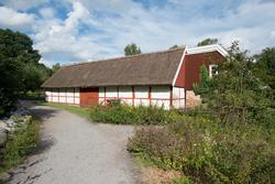 Västra loglängan. Den västra loglängan på Skånegården är uppförd i en våning i korsvirkesteknik, där facken är fyllda med lerklining på stakar och flätverk. Virket är struket med röd slamfärg och fyll...