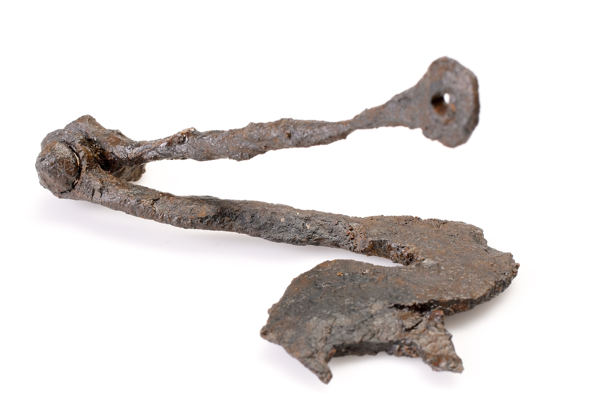 Fragment av stångbetsel till hästträns. Utgör det ena av två par S-formade sidostycken med smalare underskänklar. I underskänkelns spets finns en nit med en ögla som tjänar som axel för en ännu rörlig spiralvriden ten med runda ändplattor. Det S-formade sidstycket är platt och har en urgröpning för bettet som saknas. Även överskänkeln saknas. Samma typ som M 17001: 2087, men något enklare utformning.