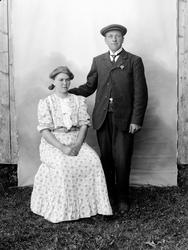 Portrett av par. Fotografens bakteppe synlig, hengt opp uten