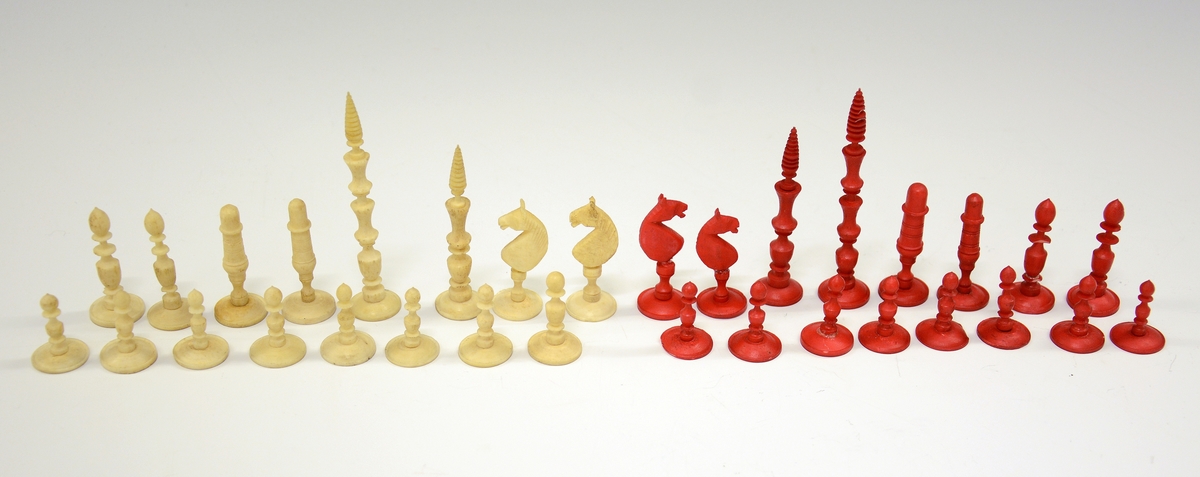 32 sjakkbrikker i ben, 16 røde og 16 hvite. Etui i tre med skyvelokk. Brett følger ikke med.