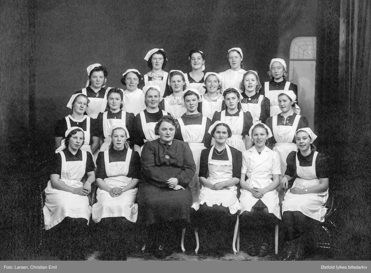 Gruppebilde av skoleelever ved Borregaard Husstelleskole i Sarpsborg 1940.

Påskrift på bakside av bildet: 
Bjørg Kristiansen gikk på Borregård husmorskole i 1940. 
Bjørg nr. 2 i andre rekke fra venstre. Liv nr. 2 i andre rekke fra høyre.
Diplom til Bjørg Kristiansen  som i 18. desember 1940 fikk følgende karakteren Meget godt i Mat og kjøkkenstell og Håndarbeide, og Særdeles godt i Orden og Opførsel. 
Diplomet er undertegnet husstellærerinne Anna-Louise Wessel. Antakelig er det hum som sitter som nummer tre fra venstre i første rekke.