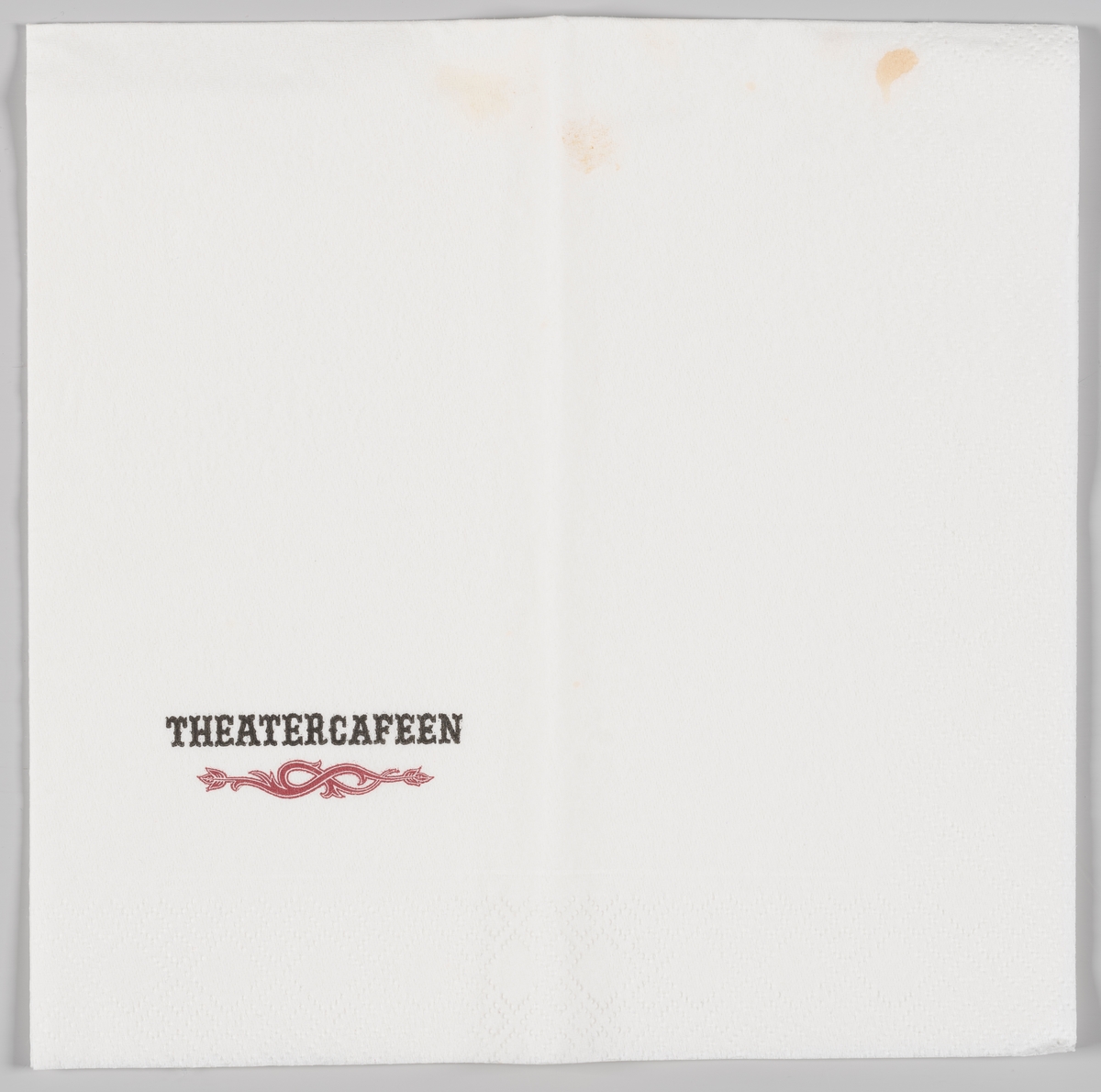 En pynteranke og reklametekst for Theatercafeen (i Oslo).

Reidun Heide som har samlet inn serviettsamlingen opplyser at hun tok denne servietten fra Theater Cafeen som eksempel i Norge Rundt, som ble vist 8. mars 1986. På Norge Rundt fortalte hun om samlingen og viste frem eksempler.
