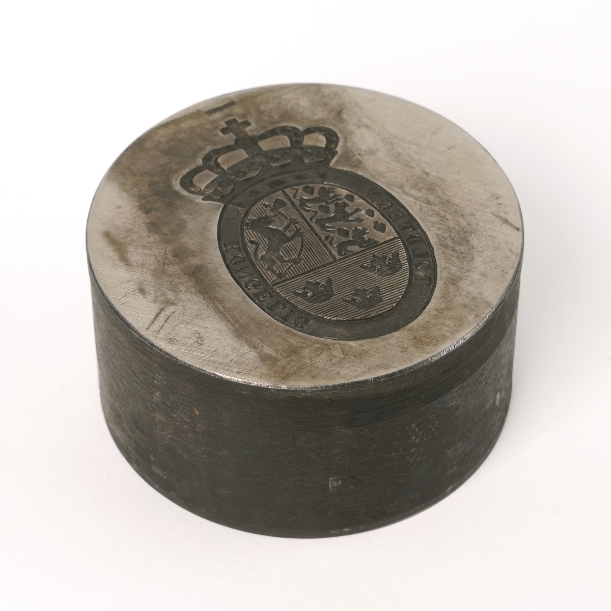 Stanse av metall med  til utstansing av kontrolltegn/tolltegn. Stansen er rund