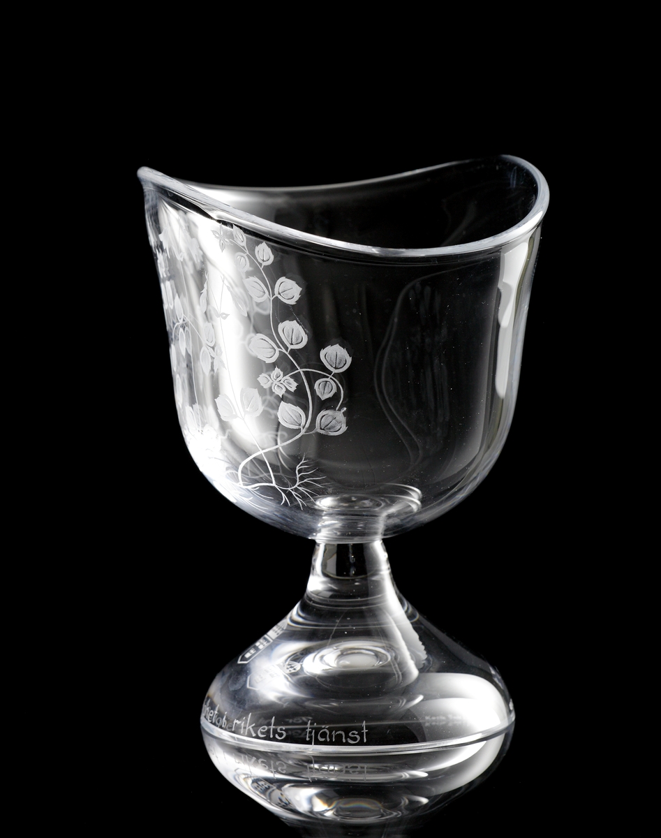 "Statstjänstemannaskålen" formgiven av Lisa Bauer. Artikelnr. 57910.
Klockformad plattad skål på trattformad fot.
Graverad dekor av linnéor och på foten riksvapnet och texten "För nit och redlighet i rikets tjänst".