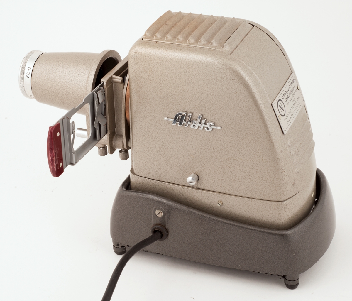 Et lite lysbildeapparat av merke ALDIS med løs skyveholder og holder for rullefilm i låsbar koffert.