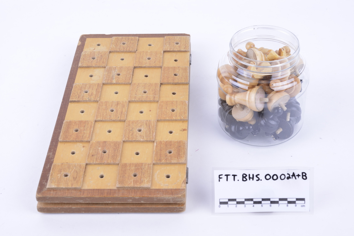 Sammenleggbar hengslet kasse i lakkert tre med brettspill på utsiden. Har tilhørende spillebrikker som ligger i en plastkrukke. 16 svarte og 16 i lakkert tre. Brikkene har pigger som kan stikkes ned i hull i brettet.