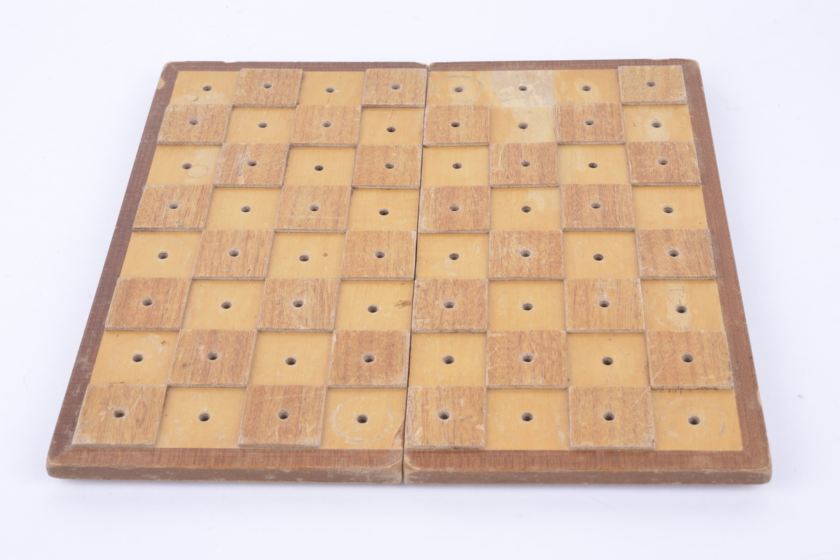 Sammenleggbar hengslet kasse i lakkert tre med brettspill på utsiden. Har tilhørende spillebrikker som ligger i en plastkrukke. 16 svarte og 16 i lakkert tre. Brikkene har pigger som kan stikkes ned i hull i brettet.