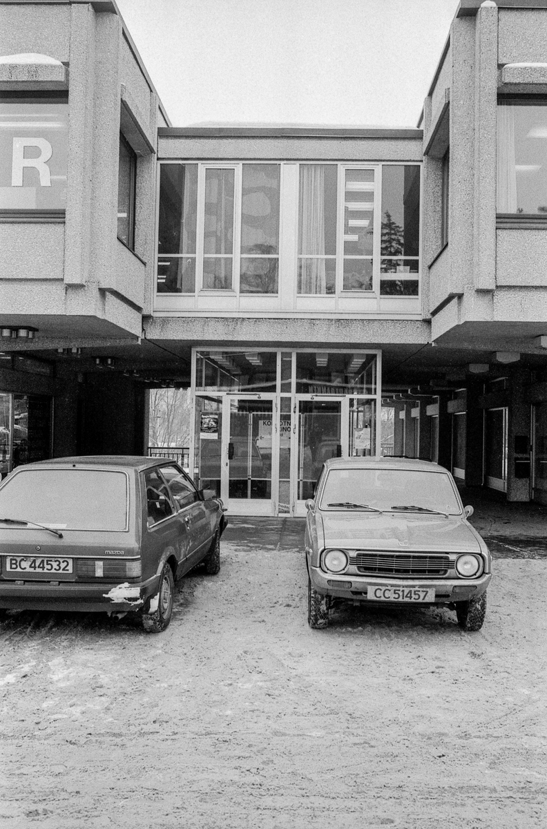 Sentrumsbygget på Kolbotn. Innganspartiet med parkerte biler foran. en mann går forbi. Rulletrappene nedenfra og ovenfra.