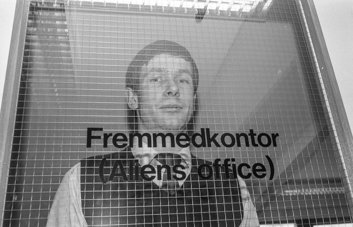 Fremmedkontoret i Ski. Politioverkonstabel Vidar Avlesen i samtale med en innvandrerkvinne i skaut. Arrangert bilde.