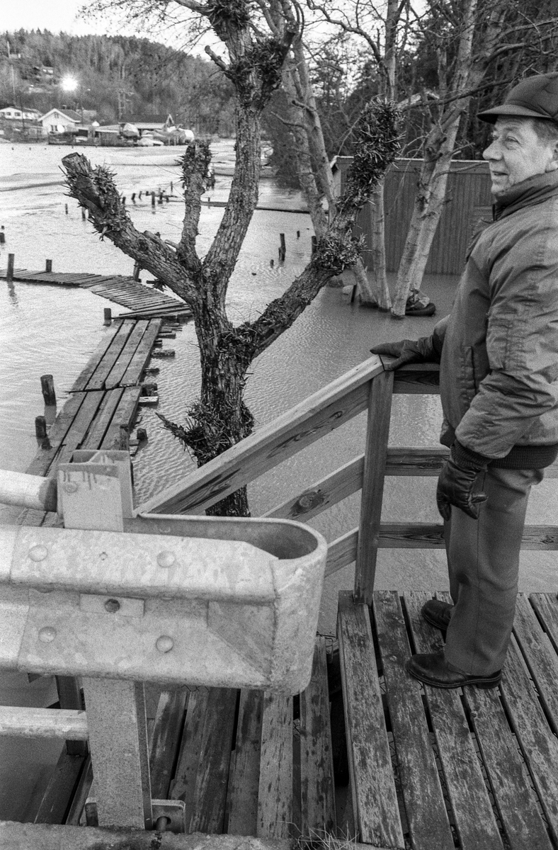 Flom ved marinaen i Son. Sjøen går opp til brygga og over trapper og gjerder. Tre menn ser på. Karlsen, Jacobsen og Hansen.