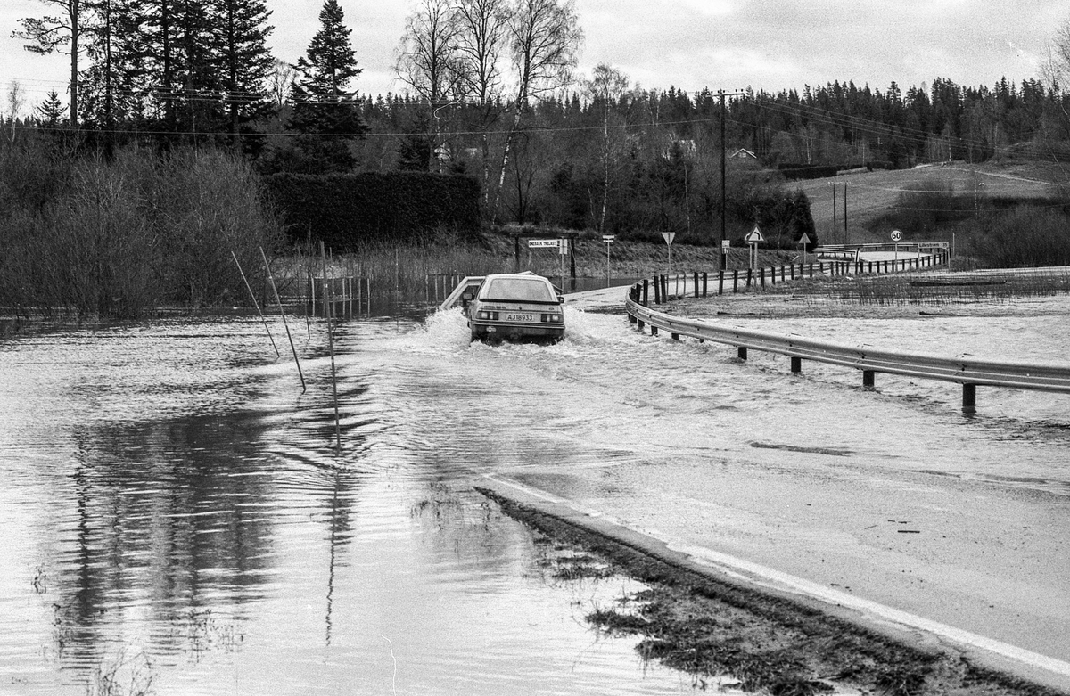 Flom i Enebakk over veier og jorder, biler kjører i flomvannet.