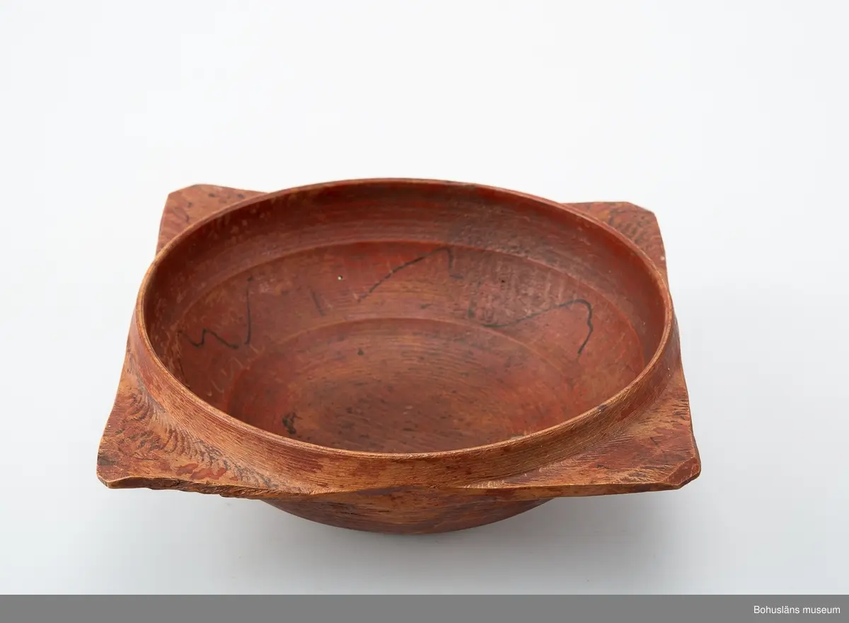 Svarvad låg skål med fyra utskjutande "snibbar" nedanför den runda mynningen. De sitter placerade i en fyrkant.
Målad i rostrött på både ut- och insida. På "snibbarna" samt inuti löper det en svart vågig dekorlinje. Inuti finns det även spår av  guldränder.
Färgen är sliten.
Skadedjursangrepp.
I botten har det suttit en äldre 'frimärksetikett'. Under botten  är "NBS" inskuret.

Se Knut Adrian Anderssons "Katalog I, A. yngre föremål" under Uddevalla museum/förening D 2A:1 i arkivet.

Förvärvad från Samuelsson, Svante Justivius; Gästgivare, Sörbo, Orust.

Litt; 
Hallset, G.: Svarvning i Ås härad, s. 25-32 och Svenningson, S.: Streckmålade toarpsaskar, s. 33-44, i Från Borås och de sju häraderna, Fässingen, 2001 - Årgång 47.
Kjellberg, Sven T, Ölets käril - Om bollar med handtag kallskålar och snibbskålar, Kulturen 1964, Lund 1964, s. 49-59.
Se bilagepärm: Kopia av tidningsartikel "Flitigt svarvande i Sjuhärad" av Gunilla Hallset i Borås Tidning lördagen den 19 maj 2001.

Ur handskrivna katalogen 1957-1958:
Snipaskål
L.22. Br. 20,5. Trä. Rödmålad. 4 hörn. Märkt: N.B.S. Föremålet helt. Hede. Bohusl.

Lappkatalog: 67