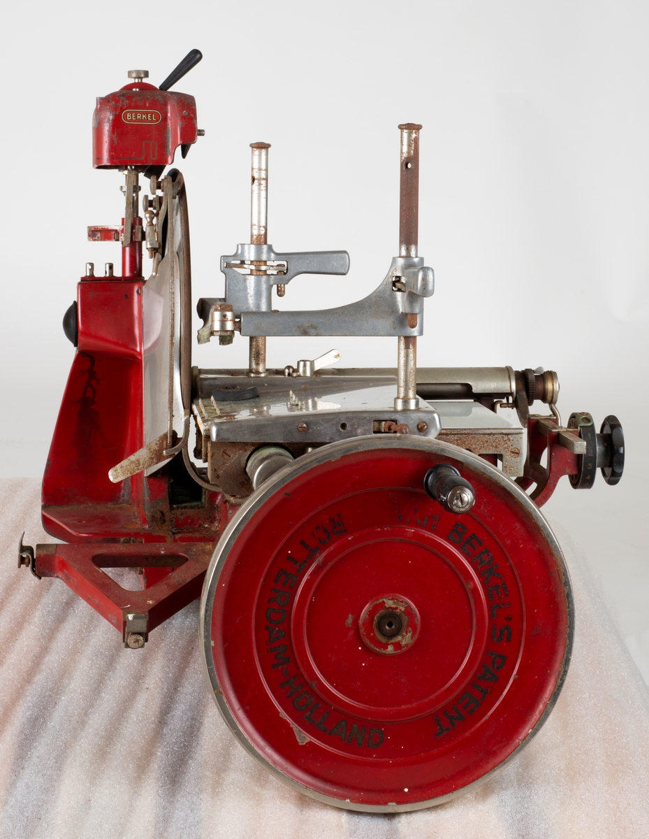 Skjæremaskin for kjøttmat i metall. Rød, blank, hvit. jern, stål og marmor
Produsert av Berkel i Rotterdam, Holland (Nederland)