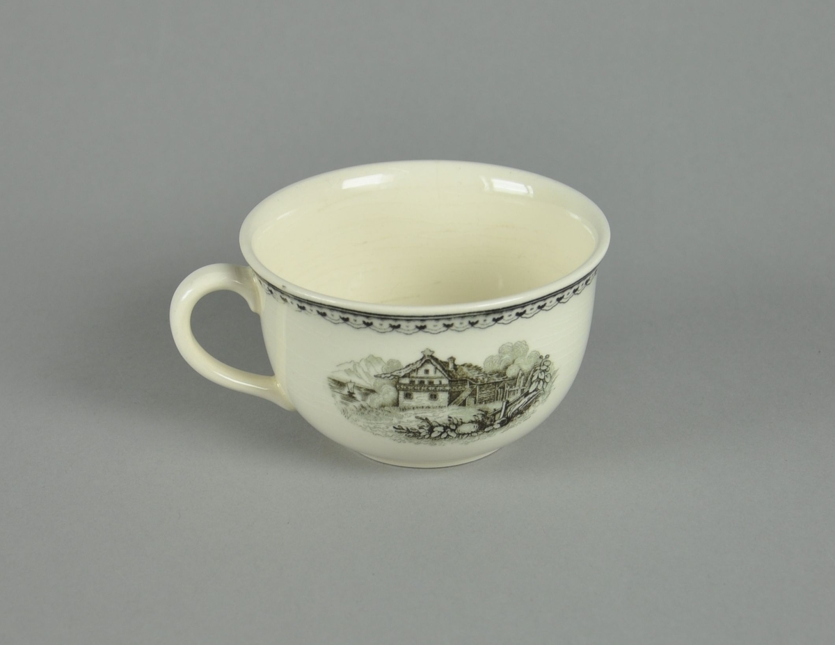 Kopp av glassert keramikk, med hank. Svart dekortrykk av klosterruiner og gård, samt en borde langs randen.