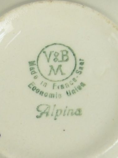 Kopp av glassert keramikk, med hank. Svart dekortrykk av klosterruiner og gård, samt en borde langs randen.