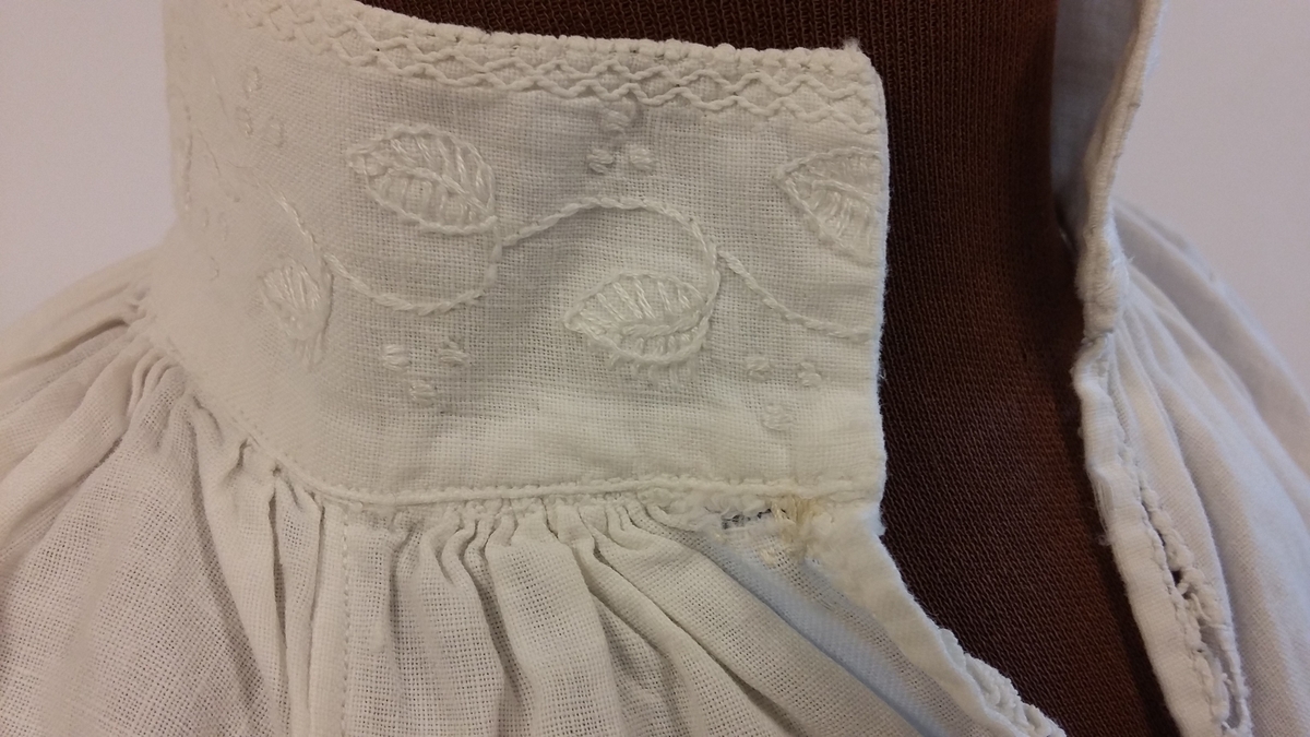 Rødt underskjørt med kappe og lomme, brodert linskjorte, brodert ull-skjørt, brodert ull-vest, brodert lue, brodert veske og blått brodérgarn i ull.