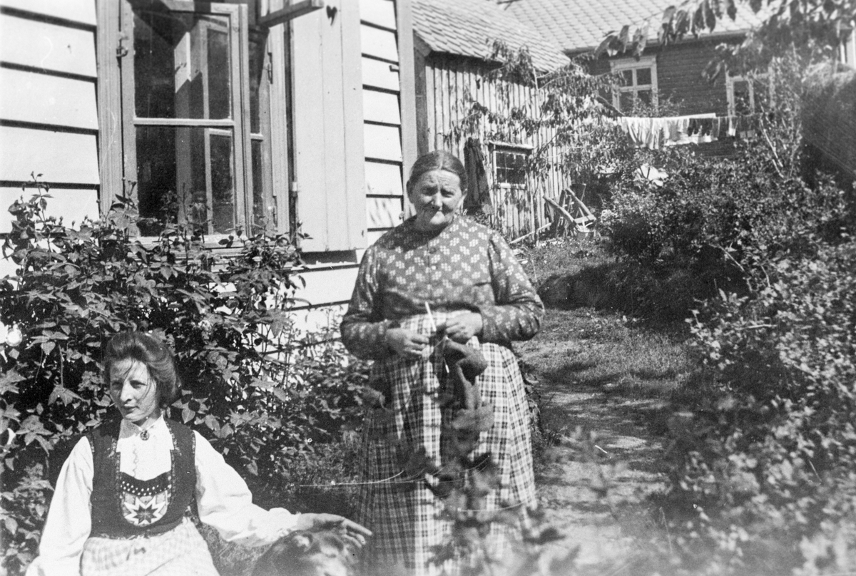 Gyda og Marita Birkeland i hagen ved gamleposten i Odda