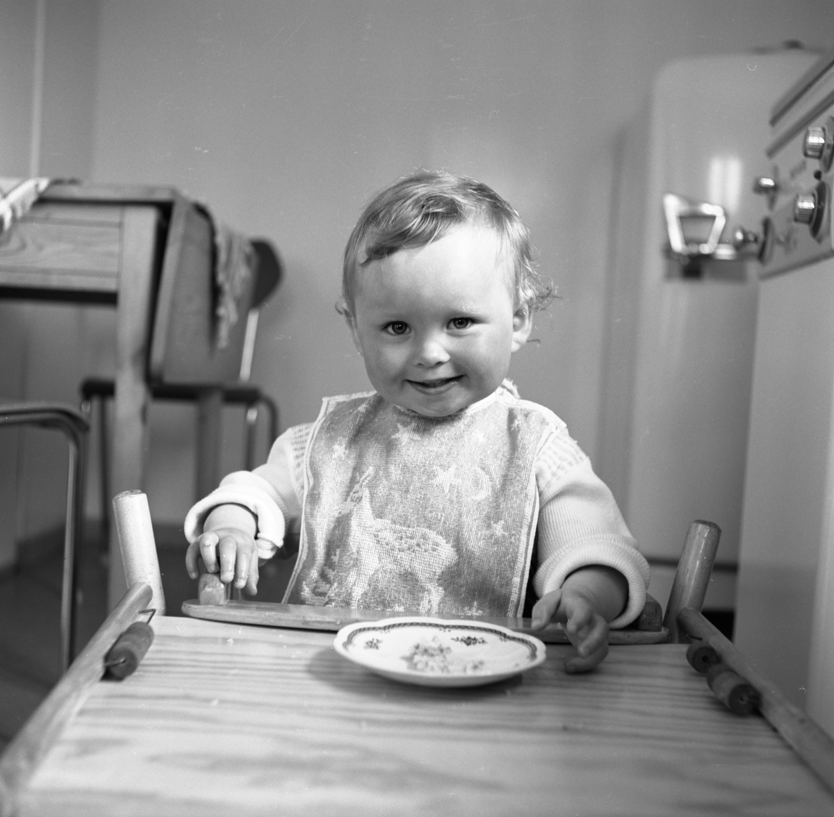 Portrettfotografi i serie av ei lita jente, Astri, som sitter i en barnestol og spiser kveldsmat.