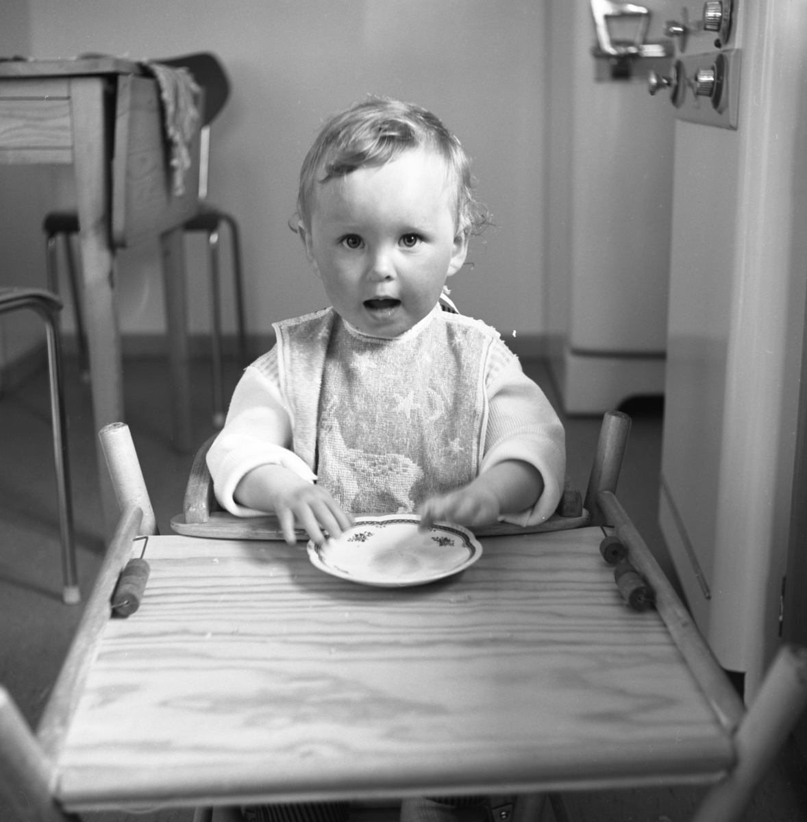 Portrettfotografi i serie av ei lita jente, Astri, som sitter i en barnestol og spiser kveldsmat.